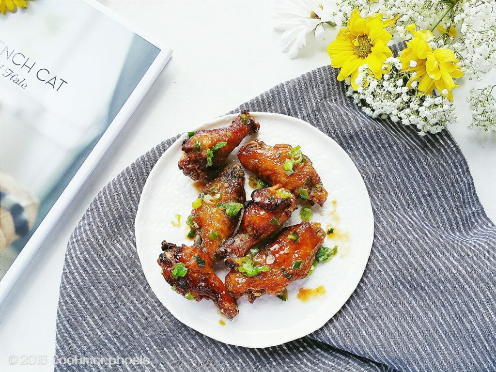 crispy twice-cooked chicken wings are put on a white plate on top of a stripe napkin