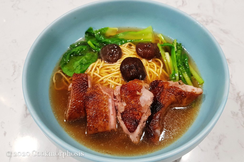 chinese duck egg noodle soup topped with roasted duck, shitake mushroom, and choy sum