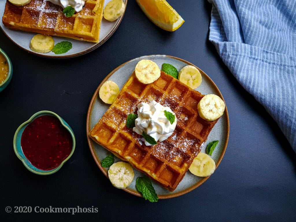easy homemade waffles topped with banana, whipped cream and mint leaves