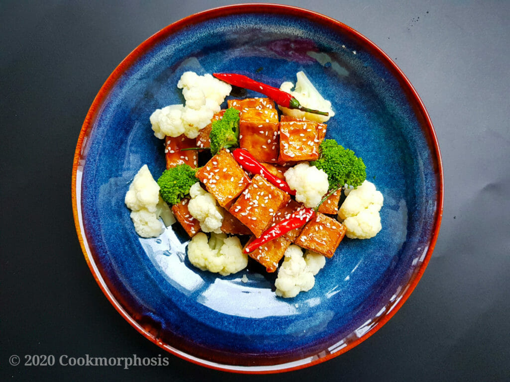 vegan chinese sesame tofu with steamed broccoli, cauliflower and toasted sesame on top