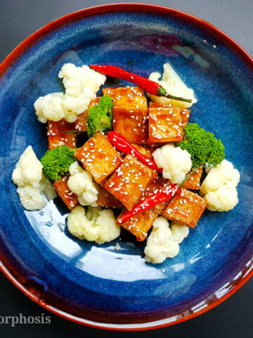 vegan chinese sesame tofu with steamed broccoli, cauliflower and toasted sesame on top