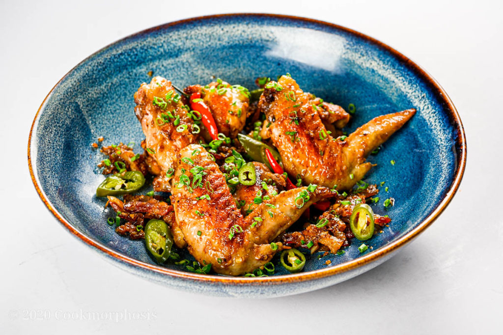 Fried confit chicken wings garnished with green onion, pickled jalapeno and thai chilies