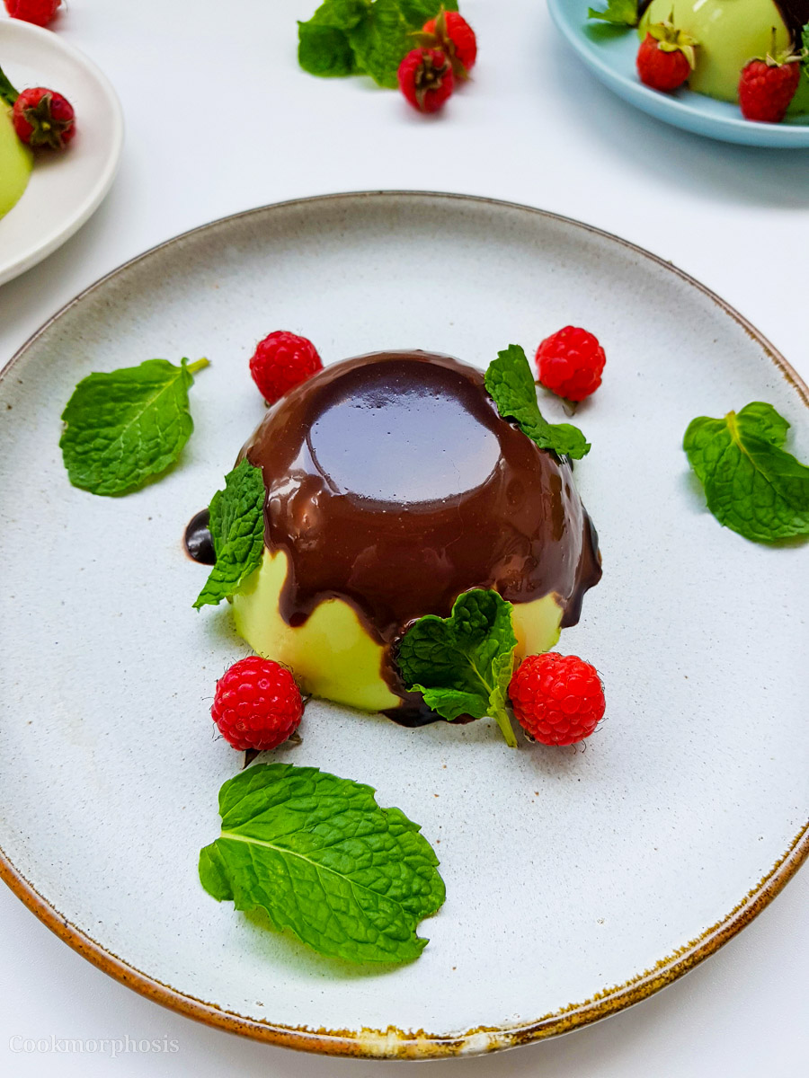Christmas Pandan Panna Cotta topped with chocolate ganache and garnished with mint leaves and raspberry