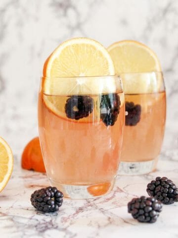 easy vodka mixed drink with slices of orange and black berries