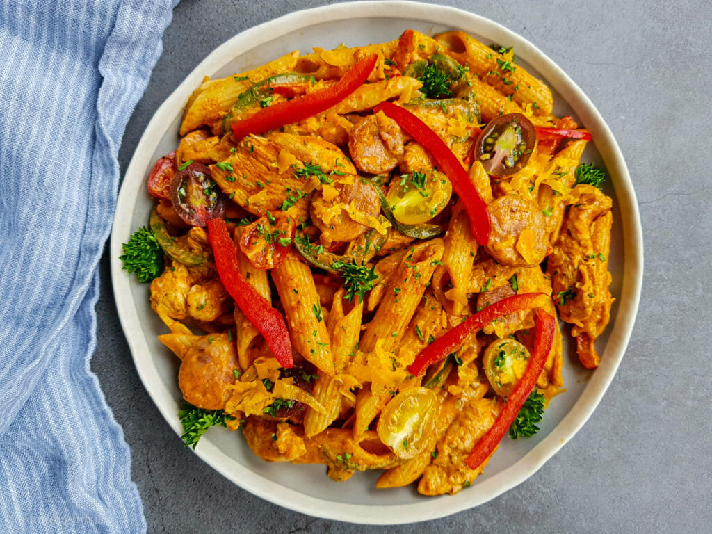 tasty and creamy cajun chicken pasta recipe topped with red bell pepper, parsley and cherry tomatoes