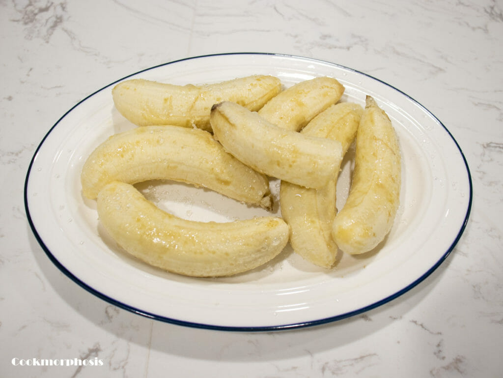 pealed and ripened bananas are seasoned with sugar and put on a white plate