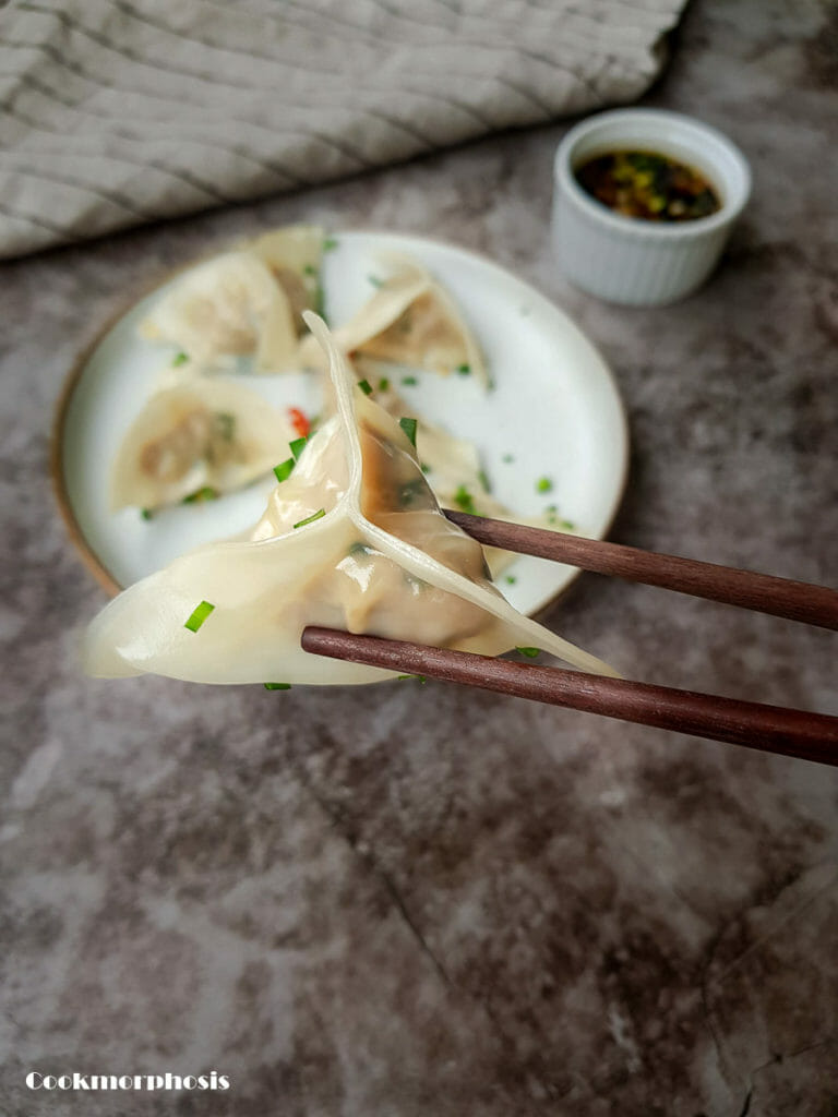 1 steamed pork and chive dumplings hold by a chopstick