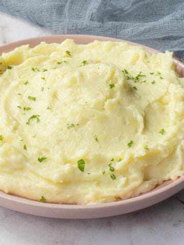 Super creamy and easy hand mashed potatoes put on a pink dish