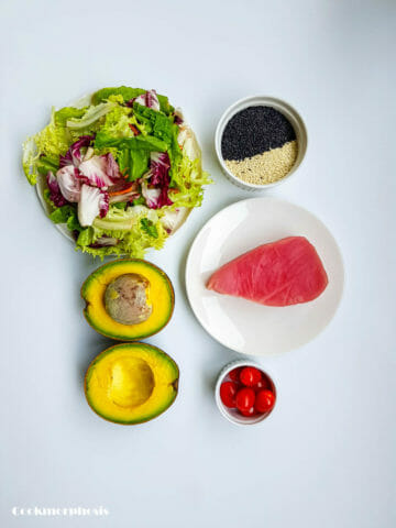 ingredients for seared tuna avocado salad: salad, white and black sesame seeds, tuna, avocado, and cherry tomatoes