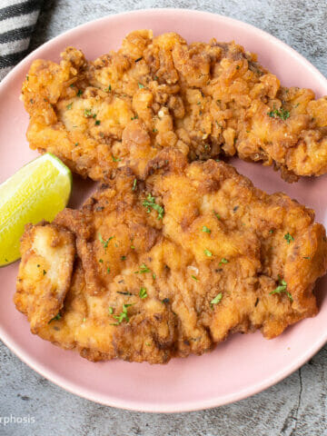 2 pieces of gluten free breaded chicken cutlets put on a plate with a lime wedge