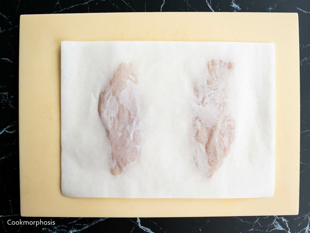 2 pieces of chicken breasts are covered with parchment paper