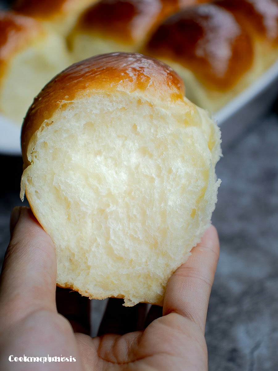 one fluffy and soft dinner roll is hold in a hand