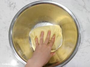 kneading by hand sweetened condensed milk dinner rolls dough in a mixing bowl