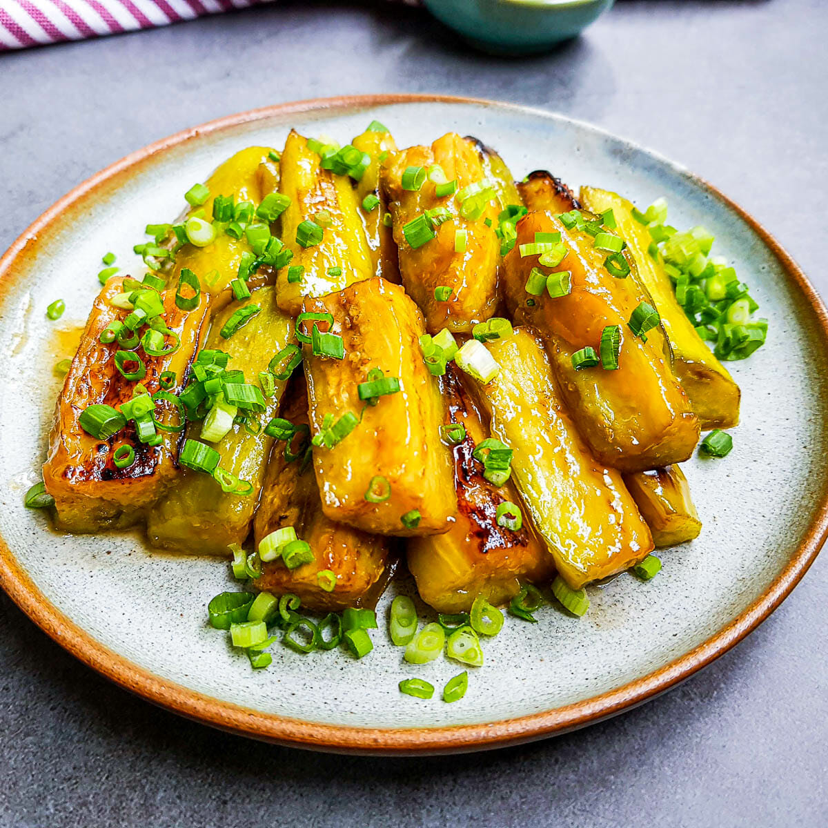 a plate of stir-fried eggplants with sweet miso sauce and garnished with green onion