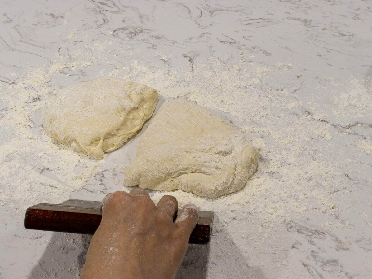 divide bread dough in half using a bench scraper
