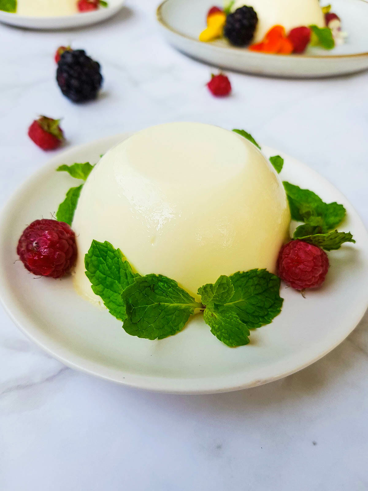 a panna cotta garnished with mint leaves and fresh raspberry