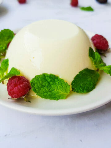 1 classic creamy panna cotta put on a plate and decorate with mint leaves and fresh raspberry