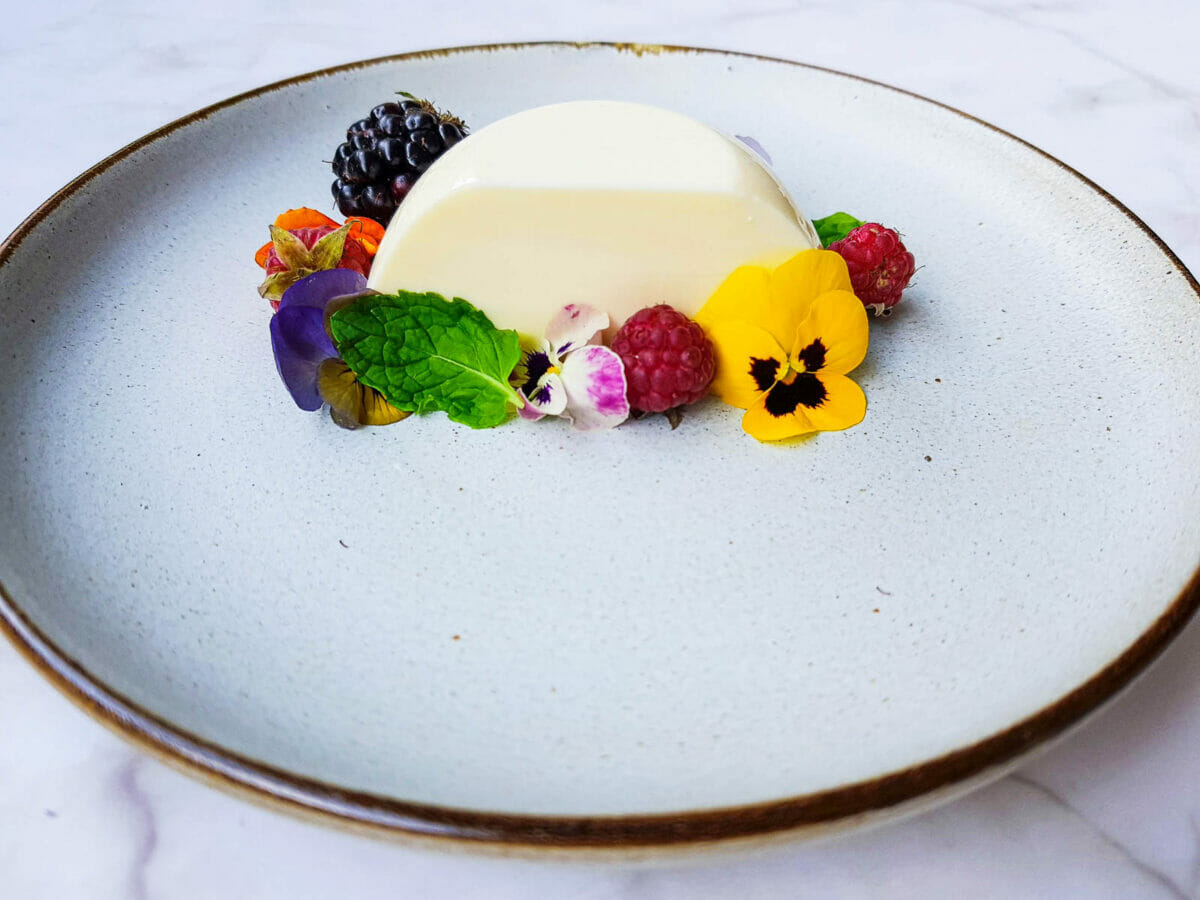 an italian pudding-like dessert also known as panna cotta is served with fresh fruit