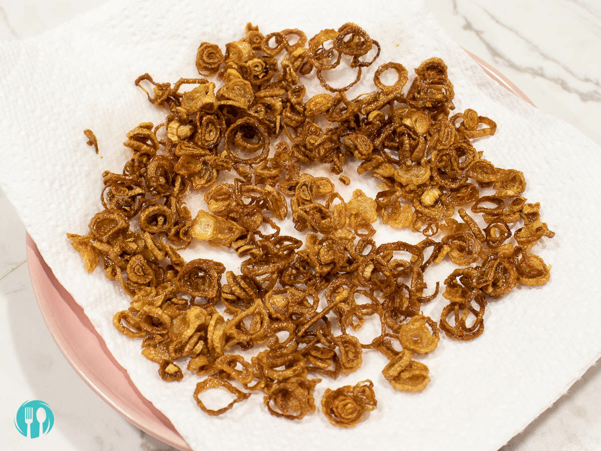 crispy fried shallot put on a pink plate lined with paper towel