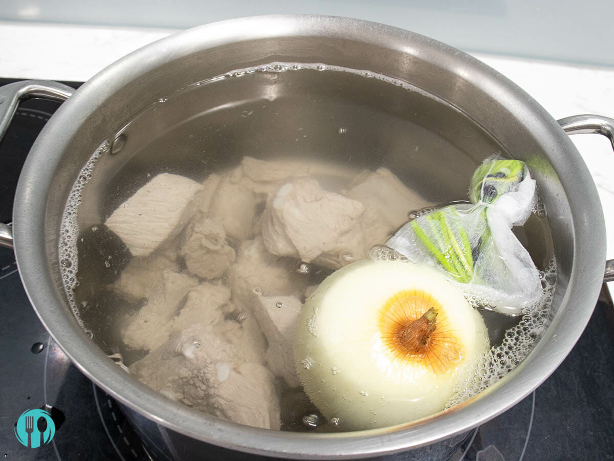 a hot water pot includes white onion, cilantro stems and pork ribs