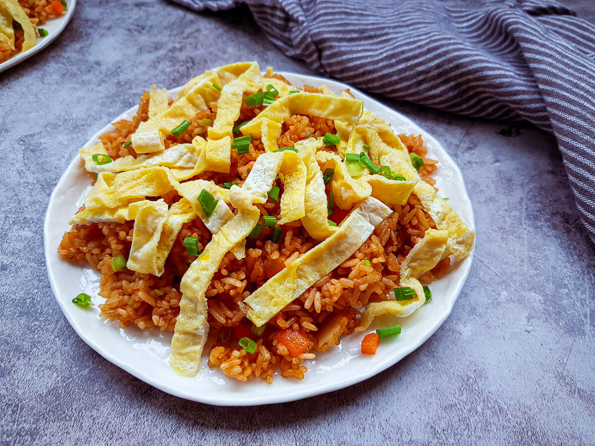a dish of sriracha fried rice topped with thinly slices of fried egg