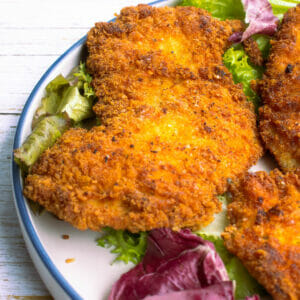 1 piece of pan-fried parmesan crusted chicken on a piece of lettuce