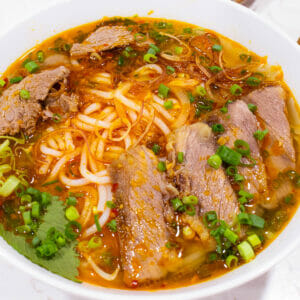 a bowl of bun bo hue topped with brisket and green onion