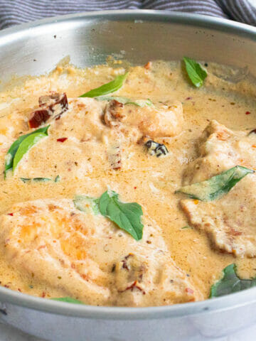 a pan of marry me chicken garnished with basil leaves
