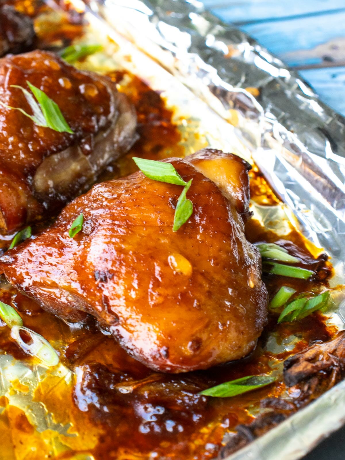 a close up of a chicken thigh made with soy sauce and garnished with chopped green onion