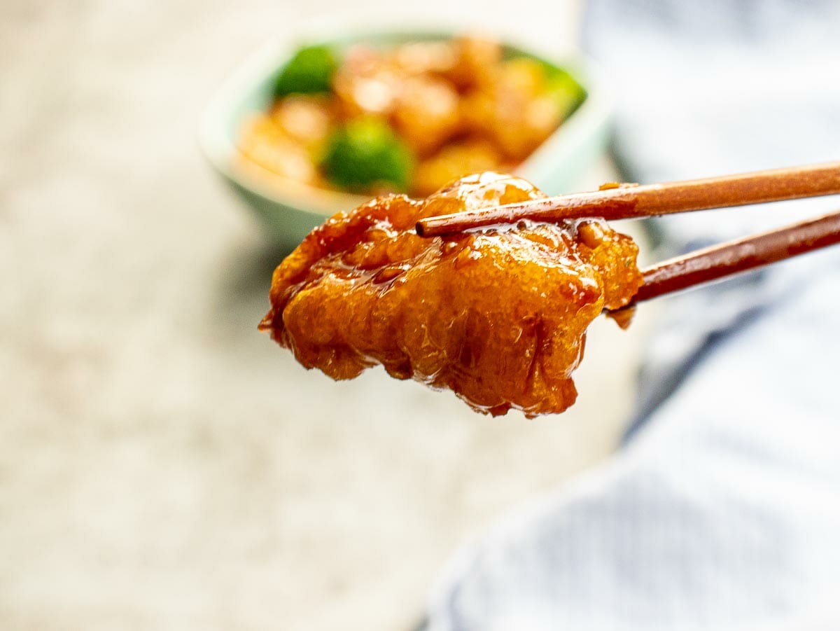 a chopstick hold a piece of crispy chicken