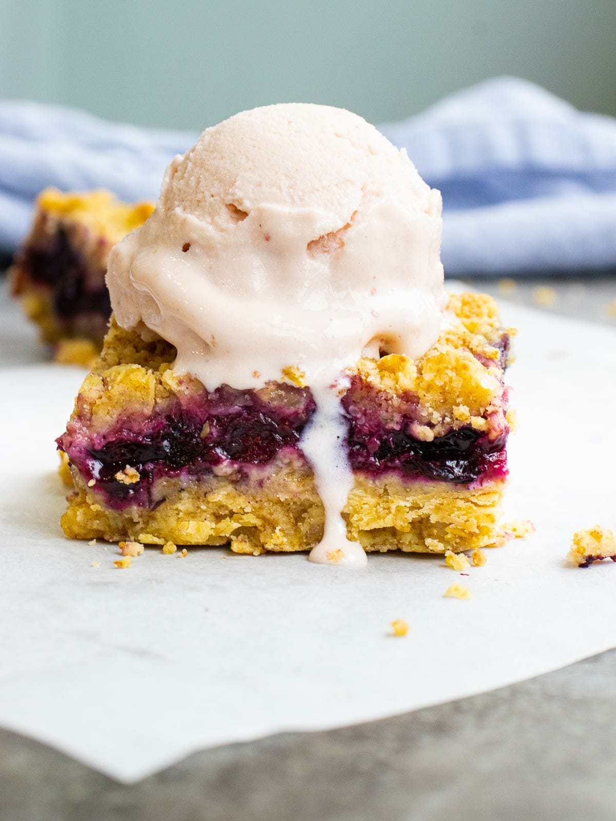 a scoop of ice cream on top of a blueberry crumble bar