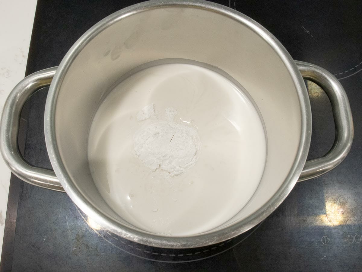 cooking coconut milk with salt and sugar in a small saucepan on stove top