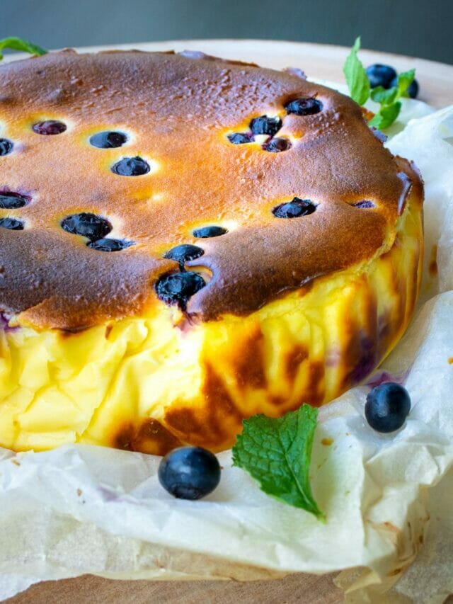 a side view of a whole cheesecake with dark brown, caramelized top