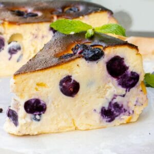 a slice of cheesecake with fresh blueberries and mint leaves