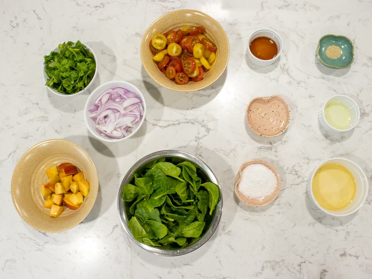 ingredients to make vinaigrette base salad: spinach, peach, tomatoes, red onion, cilantro