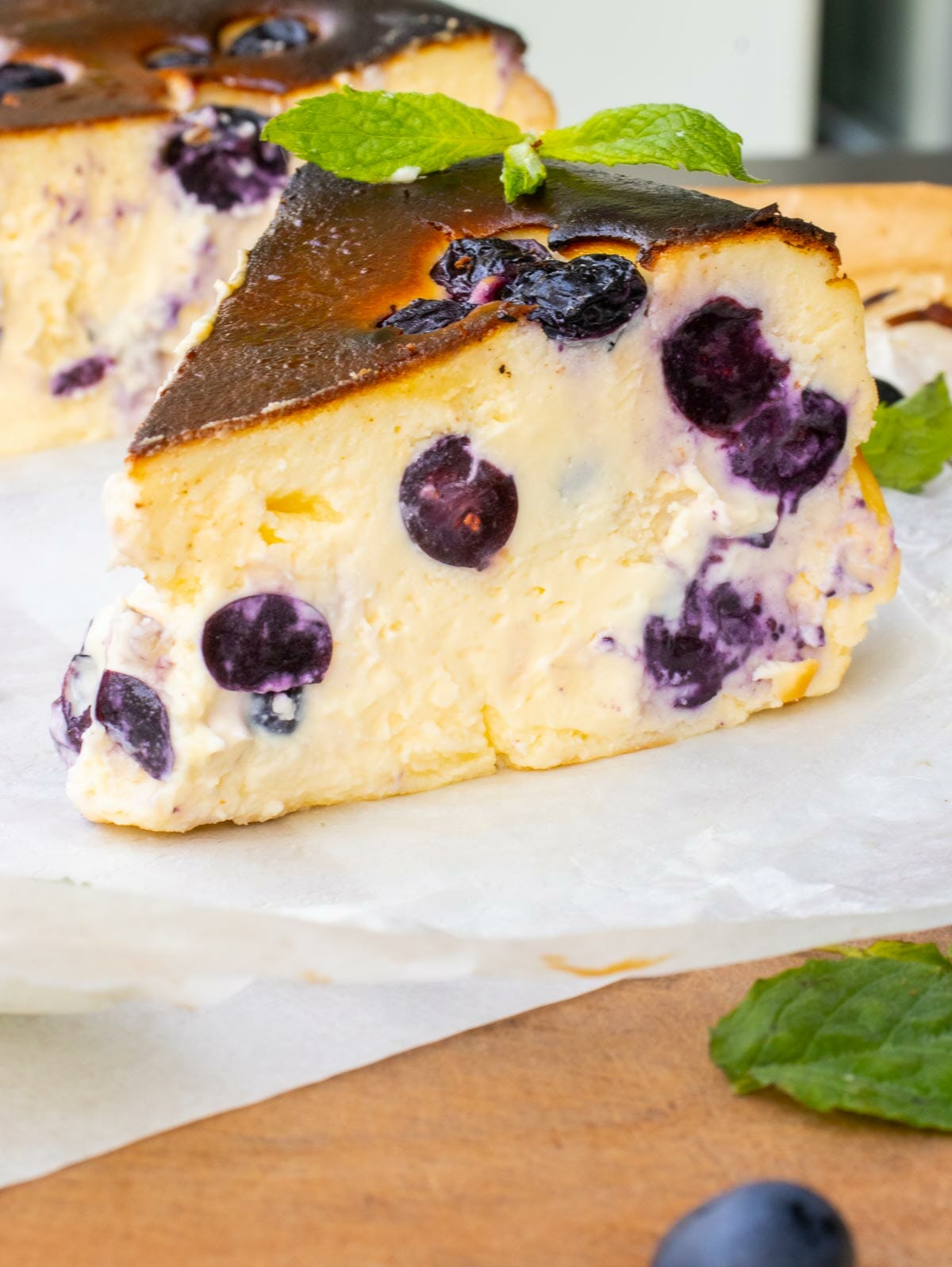 a slice of blueberry cheesecake with caramel top and garnished with mint leaves