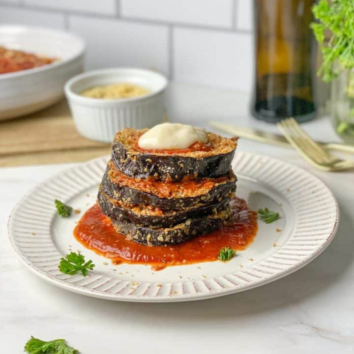 a stack of vegan eggplant parmigiana put on a white plate