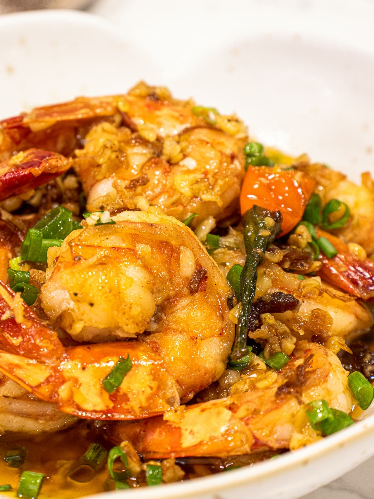 a bowl of chili garlic butter shrimp topped with chopped green onion