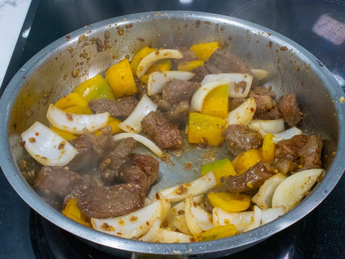 Add white onion to saute with beef and bell pepper