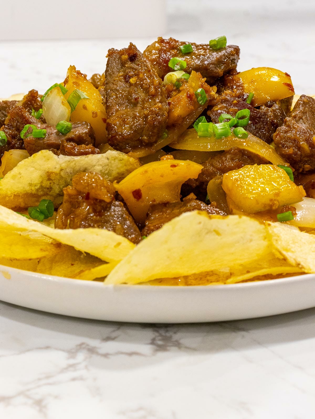 a dish of sauteed beef on the bed of potato chips