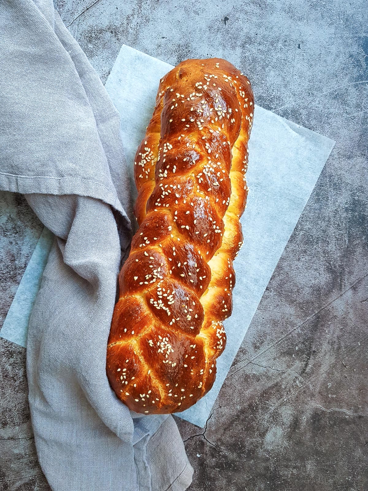 a whole challah bread put on top of a grey towel