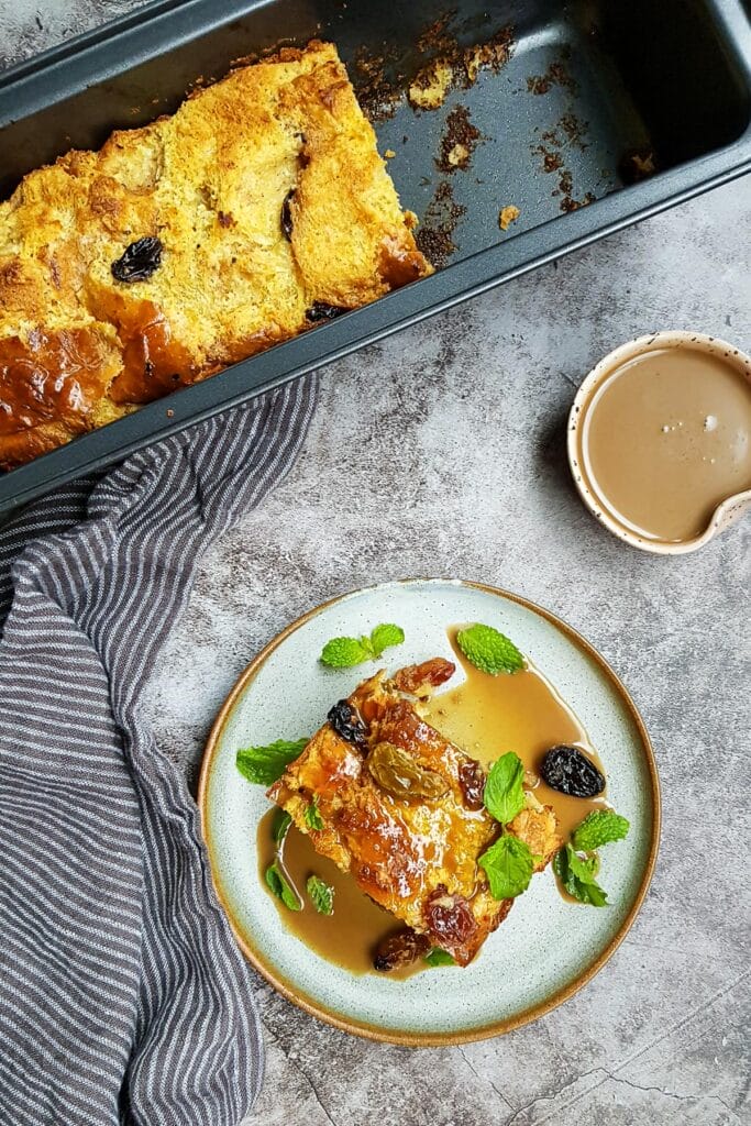 a bird eye view of a slice of brioche bread pudding put next to a whole bread pudding