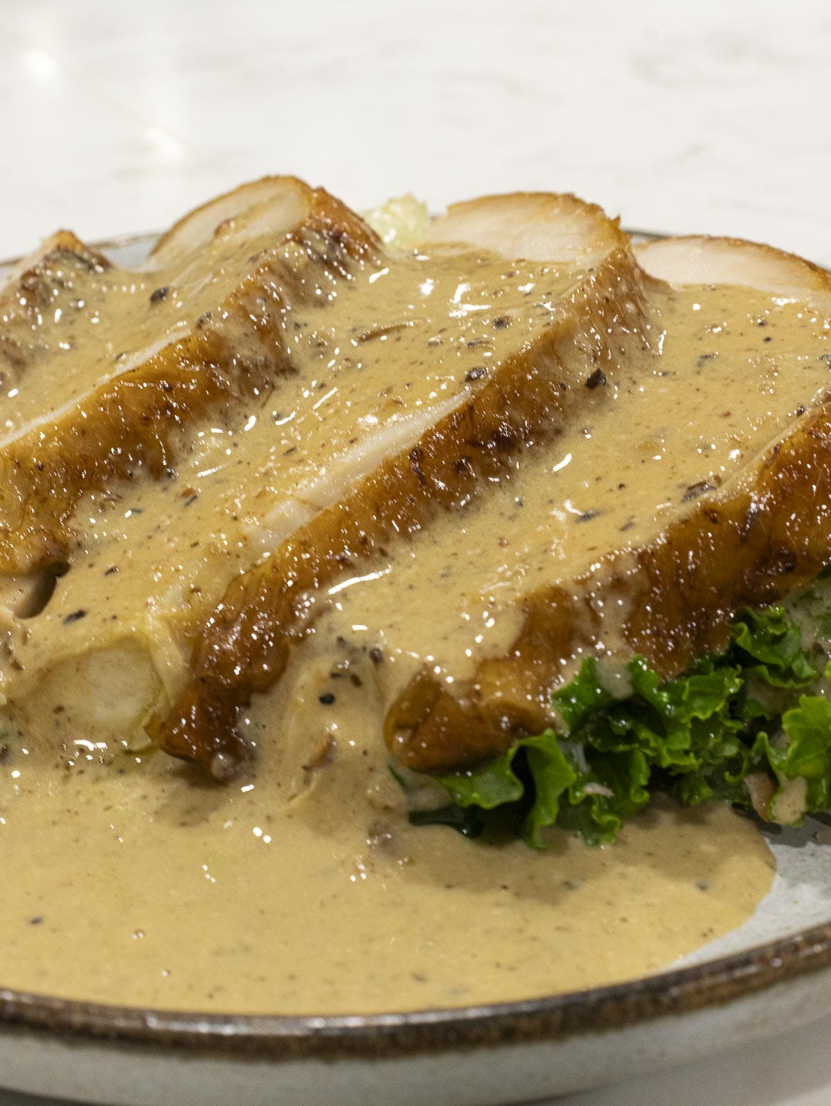 3 slices of turkey breasts put on top of a lettuce and covered in creamy gravy