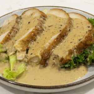 Four slices of turkey breasts are covered with creamy turkey pepper gravy