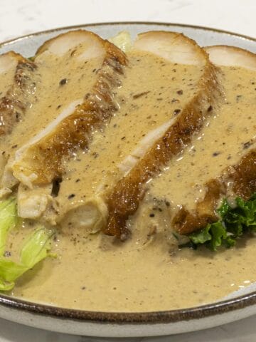 Four slices of turkey breasts are covered with creamy turkey pepper gravy