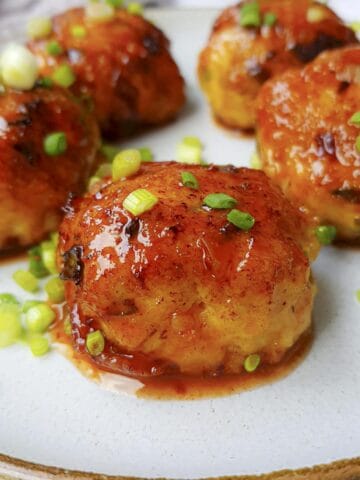 5 sweet ground turkey meatballs on a white plate and garnished with chopped green onions