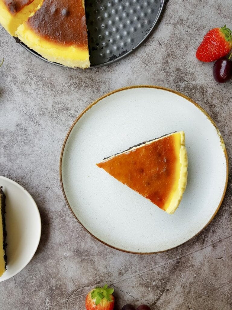 a slice new york style cheesecake put on a white plate from a bird eye view