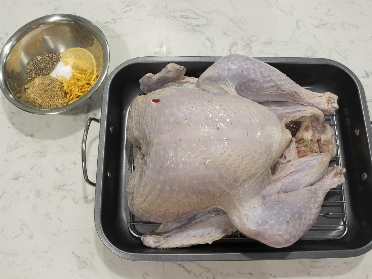 a whole uncooked turkey put next to a bowl of mixed spices