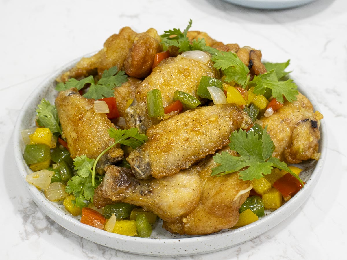 a bird eye view of a plate of fried chicken wings seasoning with salt and pepper