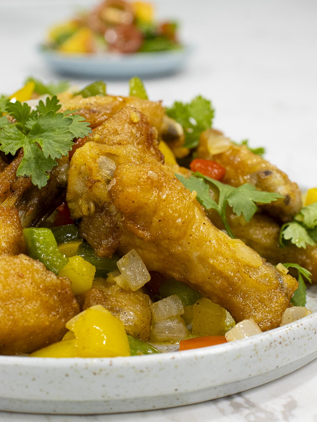 a dish of sat and pepper chicken wings garnished with cilantro leaves